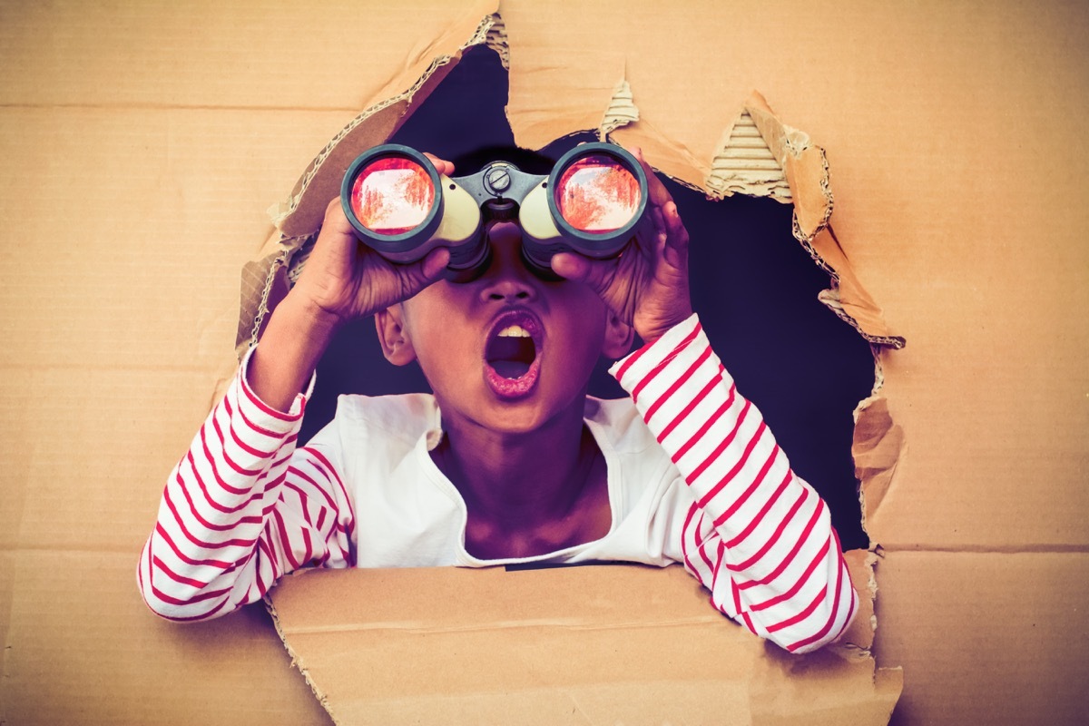 young boy in cardboard box using binoculars