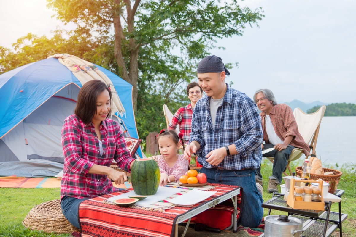 Family cutting up watermelon on a camping trip