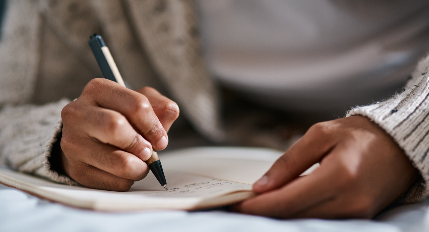 Person writing in a journal. 