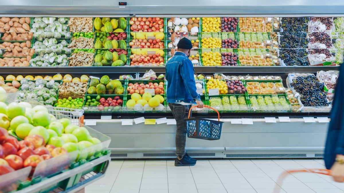 At the Supermarket: Happy Stylish Guy with Shopping Basket Shopping for Organic Fruits and Vegetables in the Fresh Produce Section of the Store.