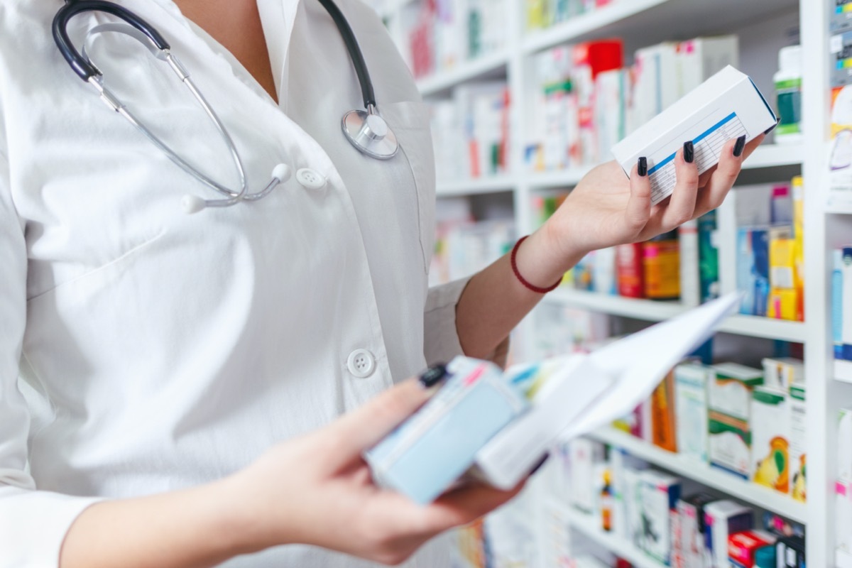 hand of woman pharmacist with prescription and medicine at drugstore