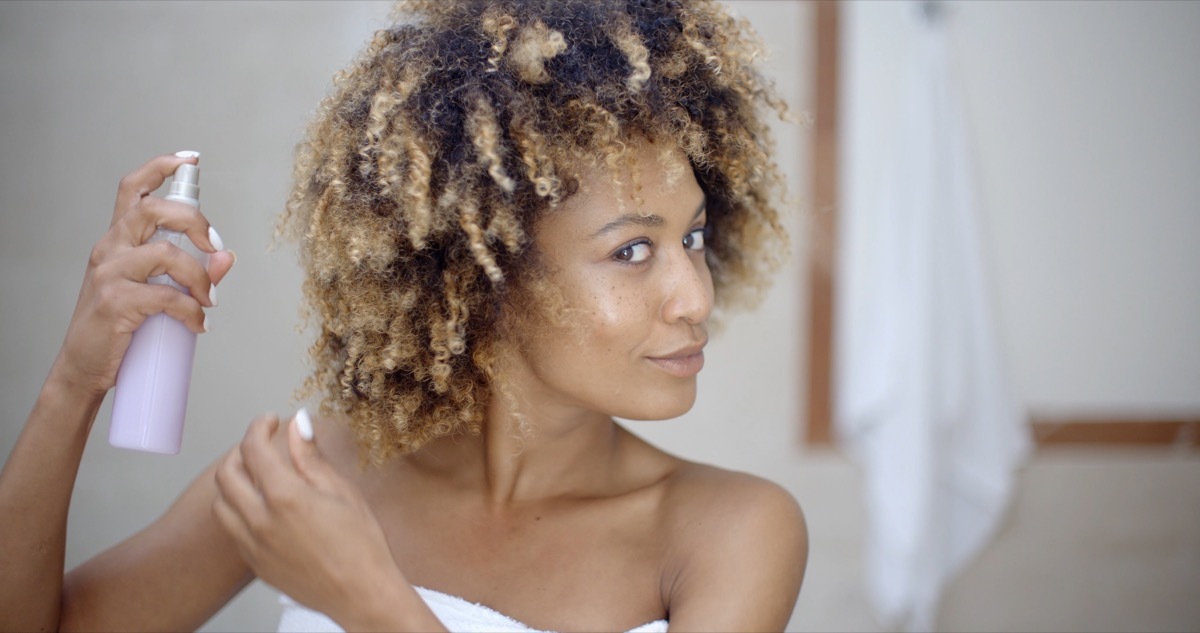 Young woman in towel using hair spray in bathroom - Image