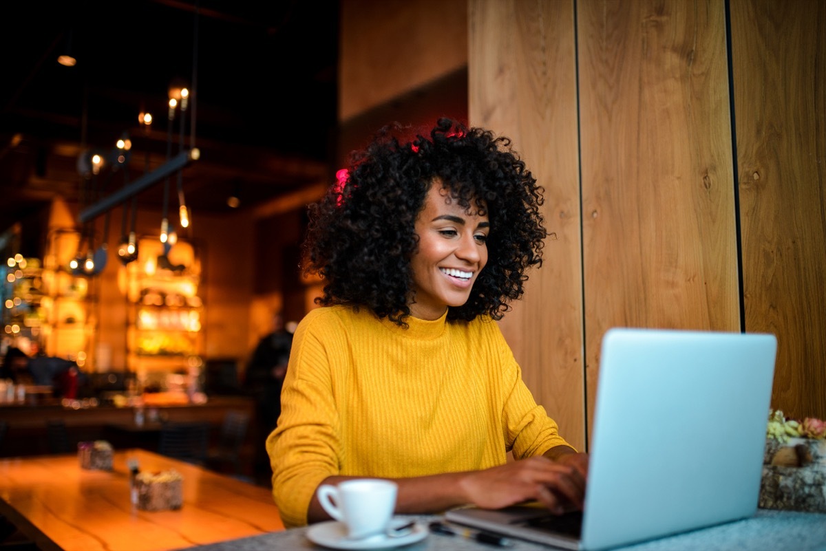 young black woman working on her laptop at a coffee shop