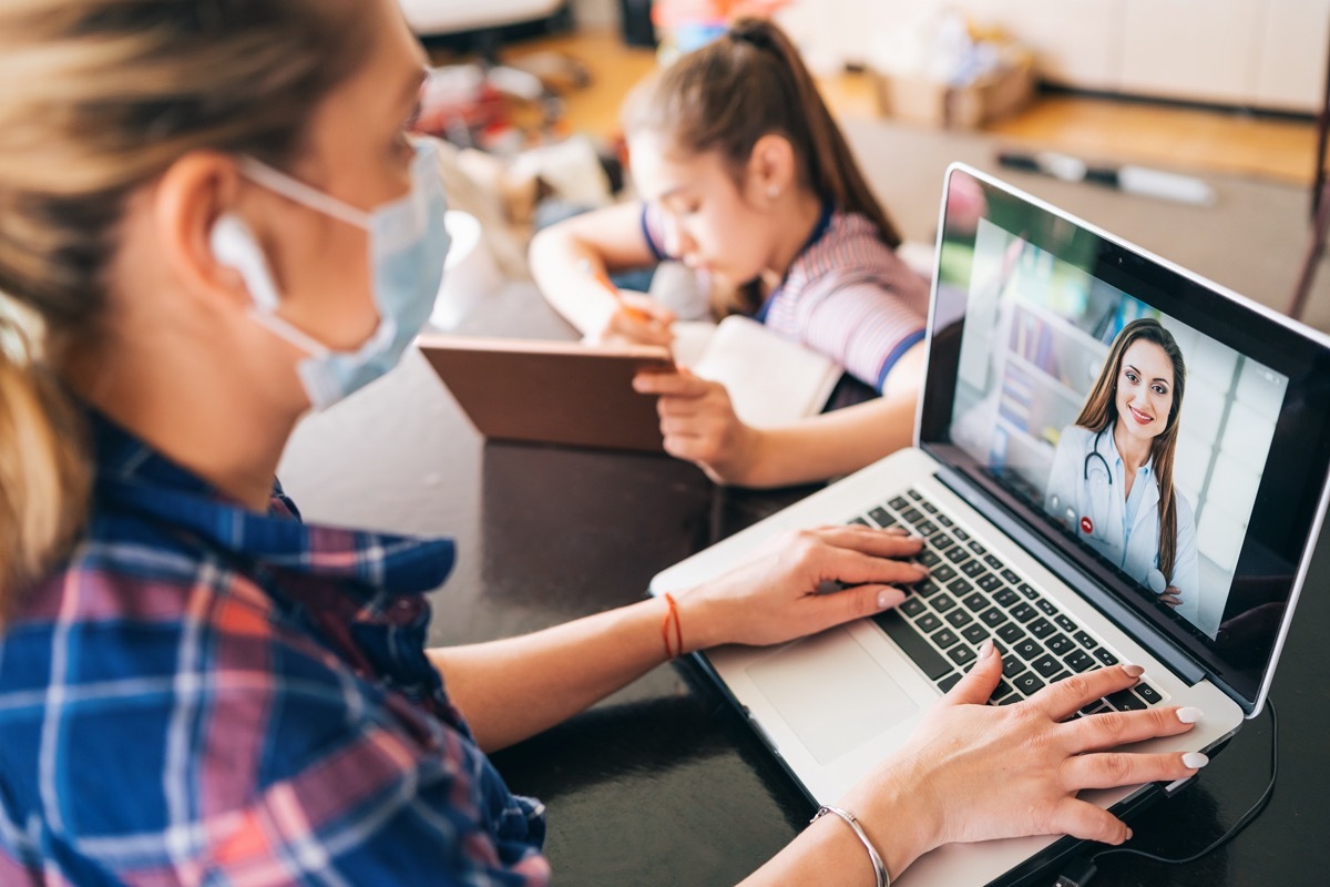 Woman using protective mask talking with doctor on laptop isolation at home for virus