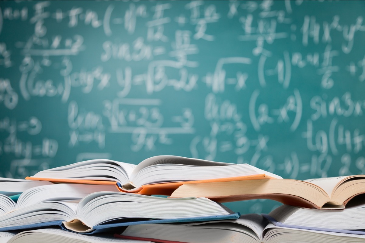 math books on table in front of white board with math problems for math jokes