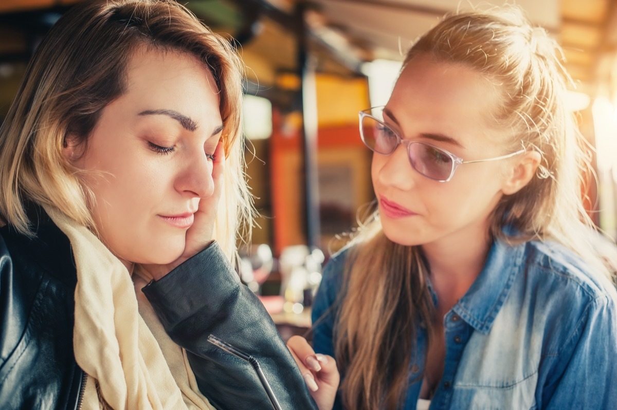 woman comforting sad friend at restaurant