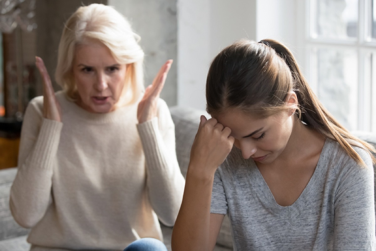 younger woman with head in hands while older woman with white hair yells at her