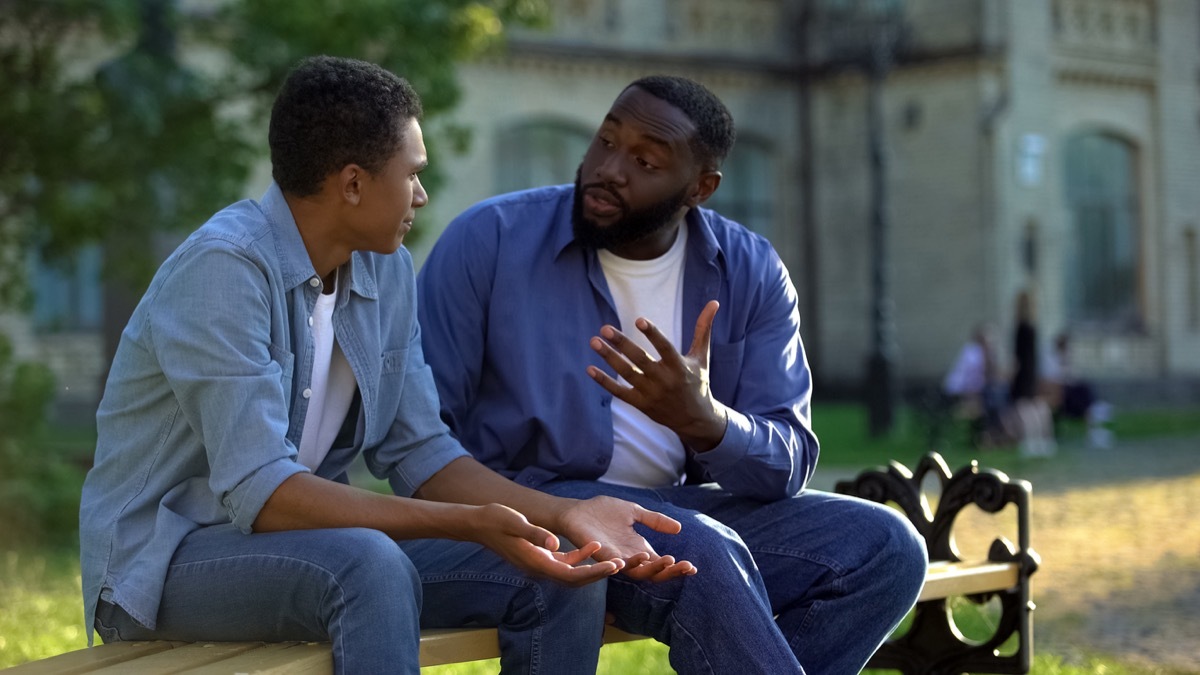 father arguing with son on bench outside