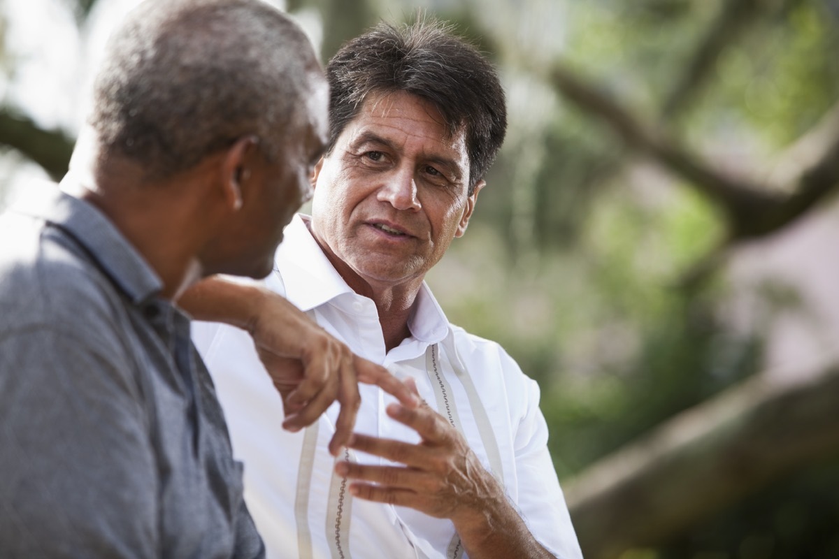 en (50s and 60s) sitting outdoors, having conversation