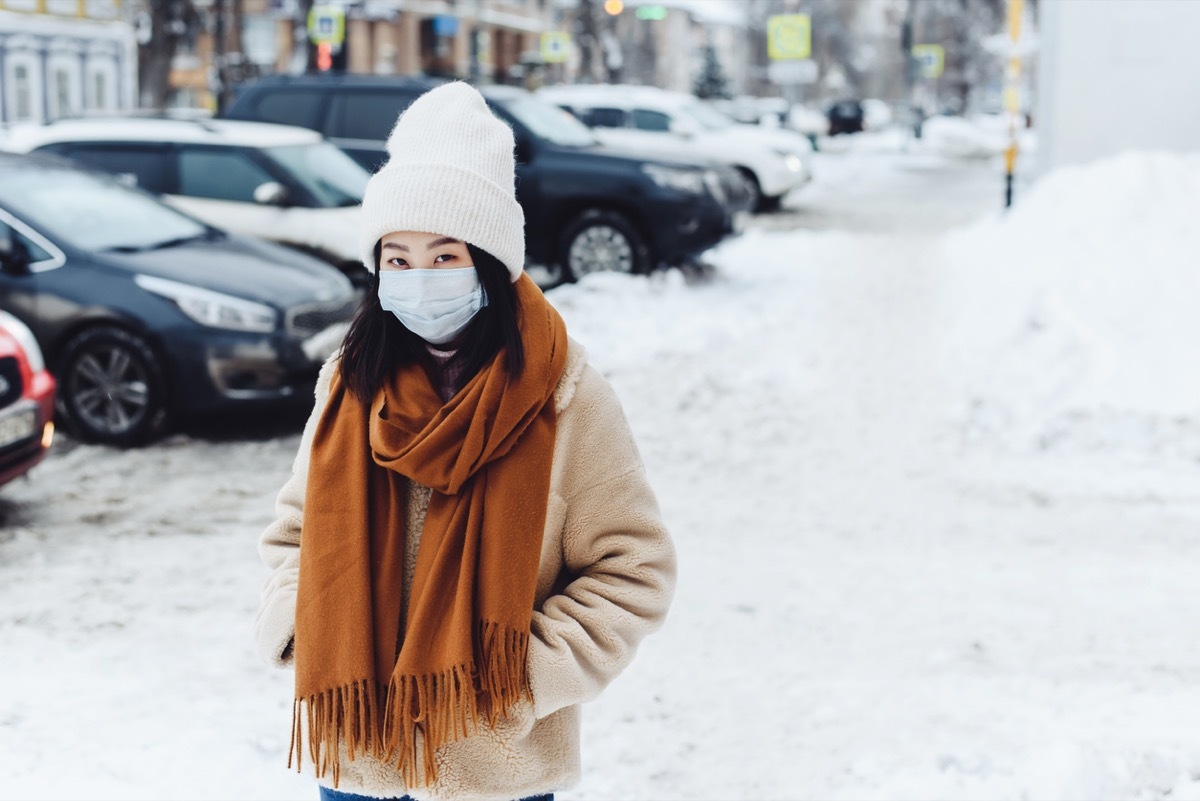 woman wearing face mask and winter clothing outside in the snow