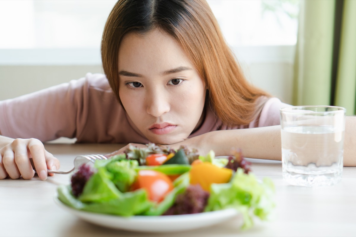 sad asian woman eating salad