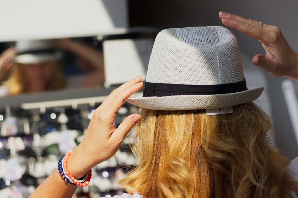 Woman trying on a hat at the market.