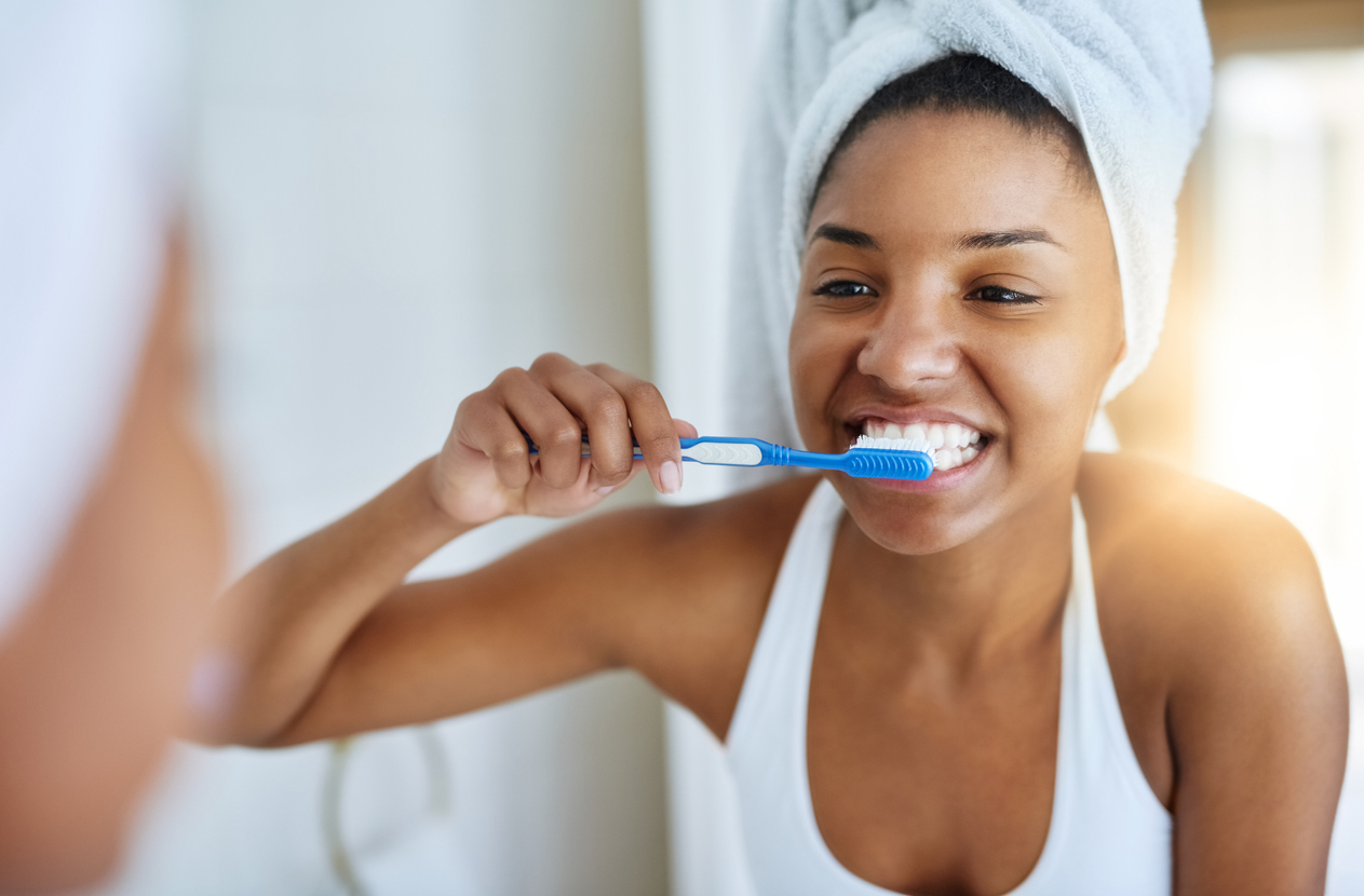 Woman brushing her teeth in the bathroom mirror.