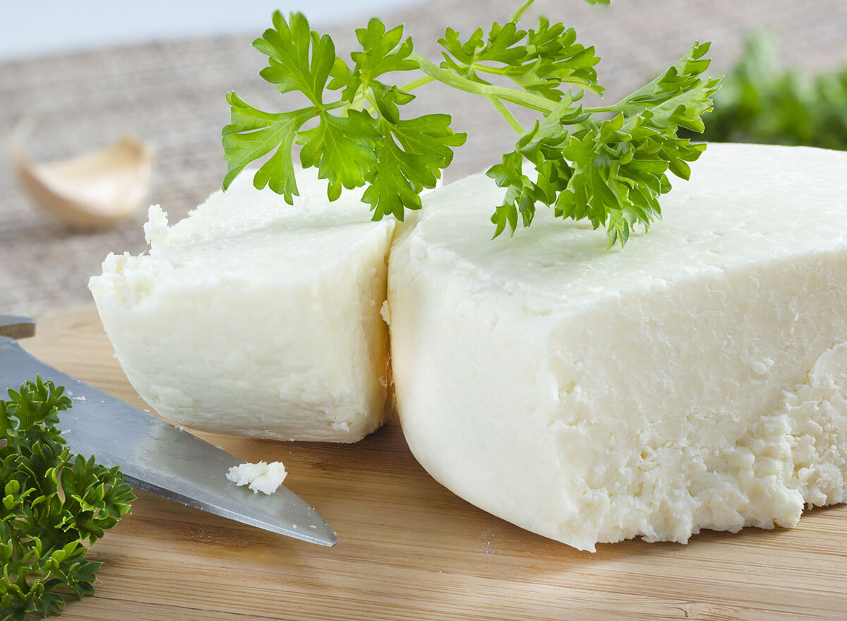 cotija cheese with cilantro cut up on a cutting board