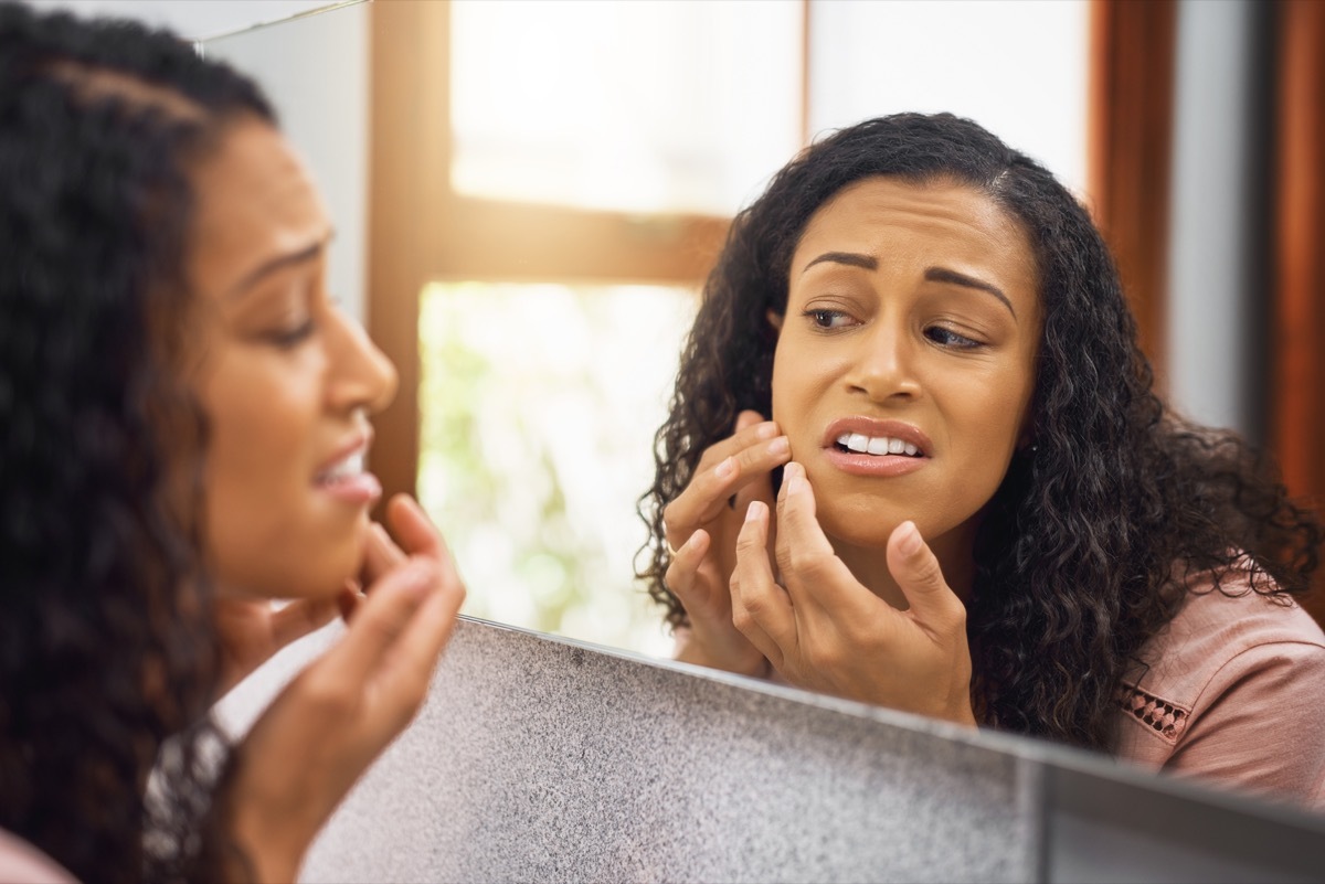 Woman checking her skin in the mirror