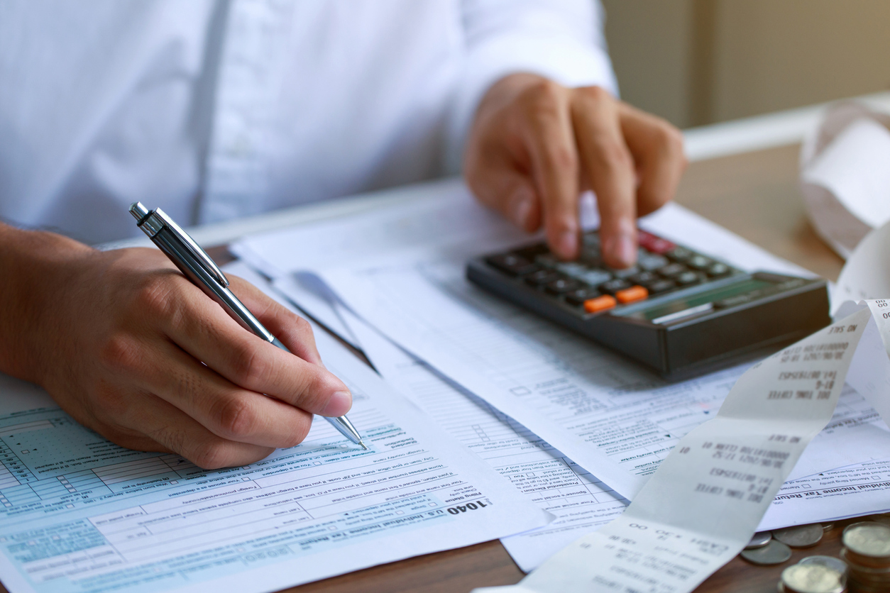 A close up of someone filling out their 1044 tax form using a calculator