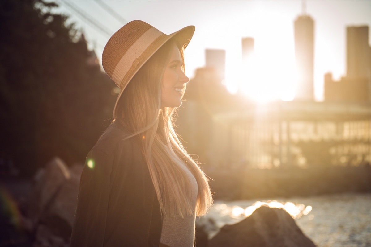 woman smiling while walking along a city waterfront - cheesy affirmations