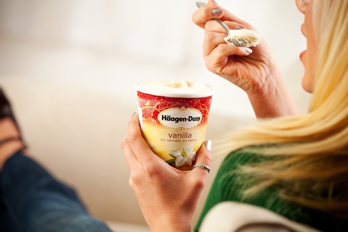 Woman eating vanilla ice cream straight from the container