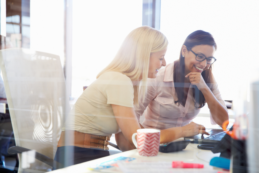 two women joking around their desk, how parenting has changed