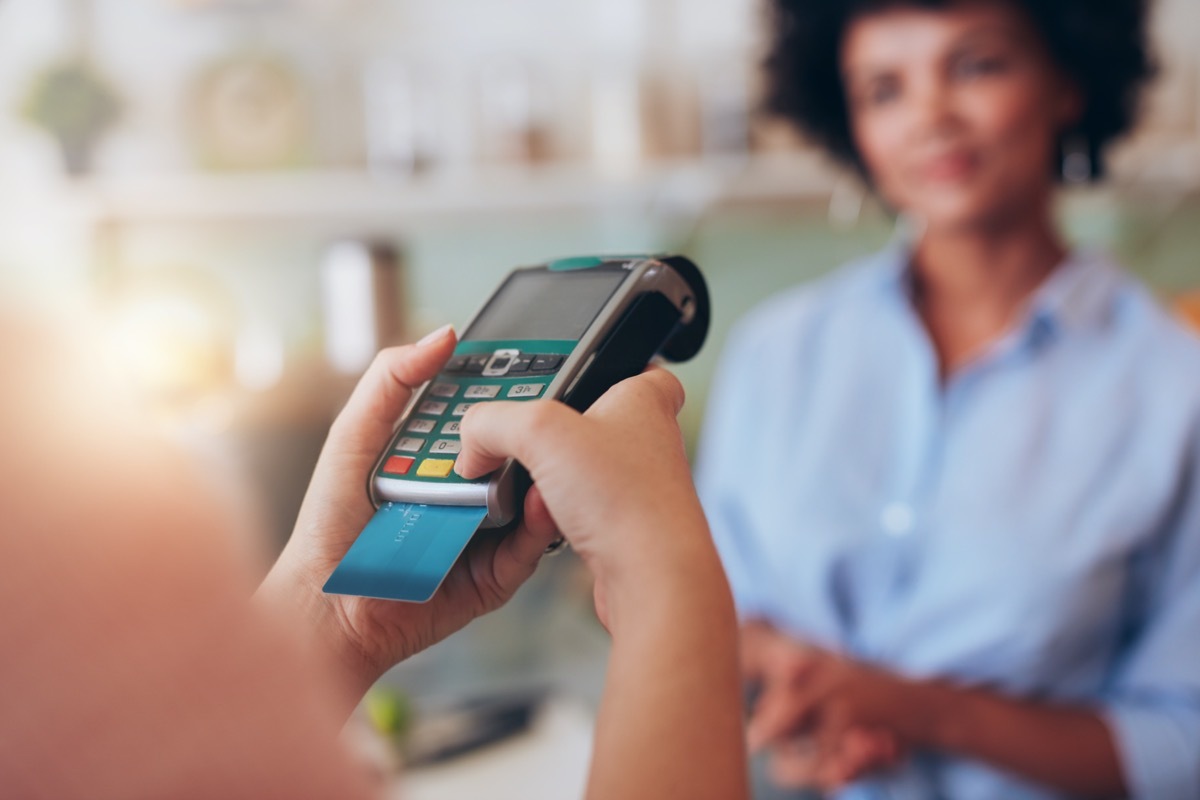 woman paying by credit card at juice bar. Focus on woman hands entering security pin in credit card reader