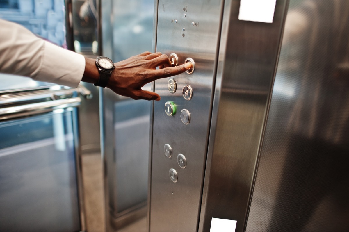 close up of man hand with watches at elavator or modern lift, pushing button.