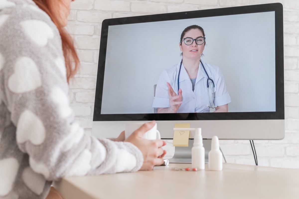 A woman with a respiratory illness is quarantined and is talking to a GP on a webcam. A doctor for an online consultation for a sick patient.