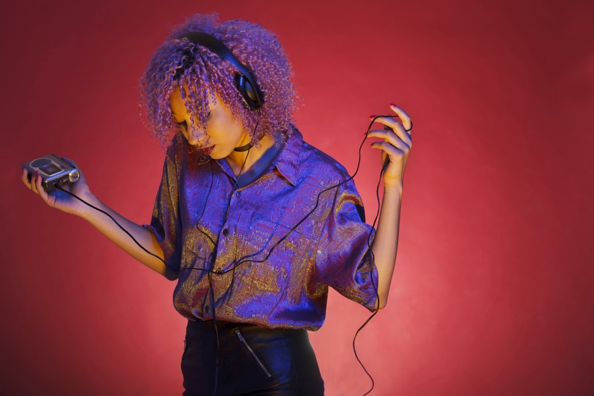 young african american woman with vintage clothes listening to music with her walkman - Image