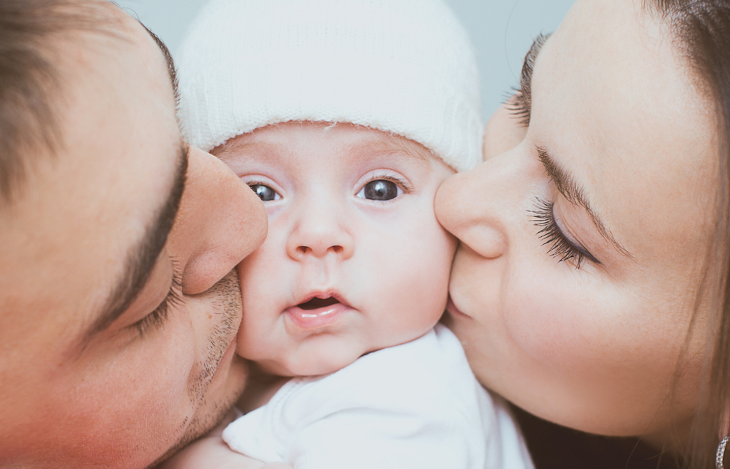 Parents kissing baby's cheeks