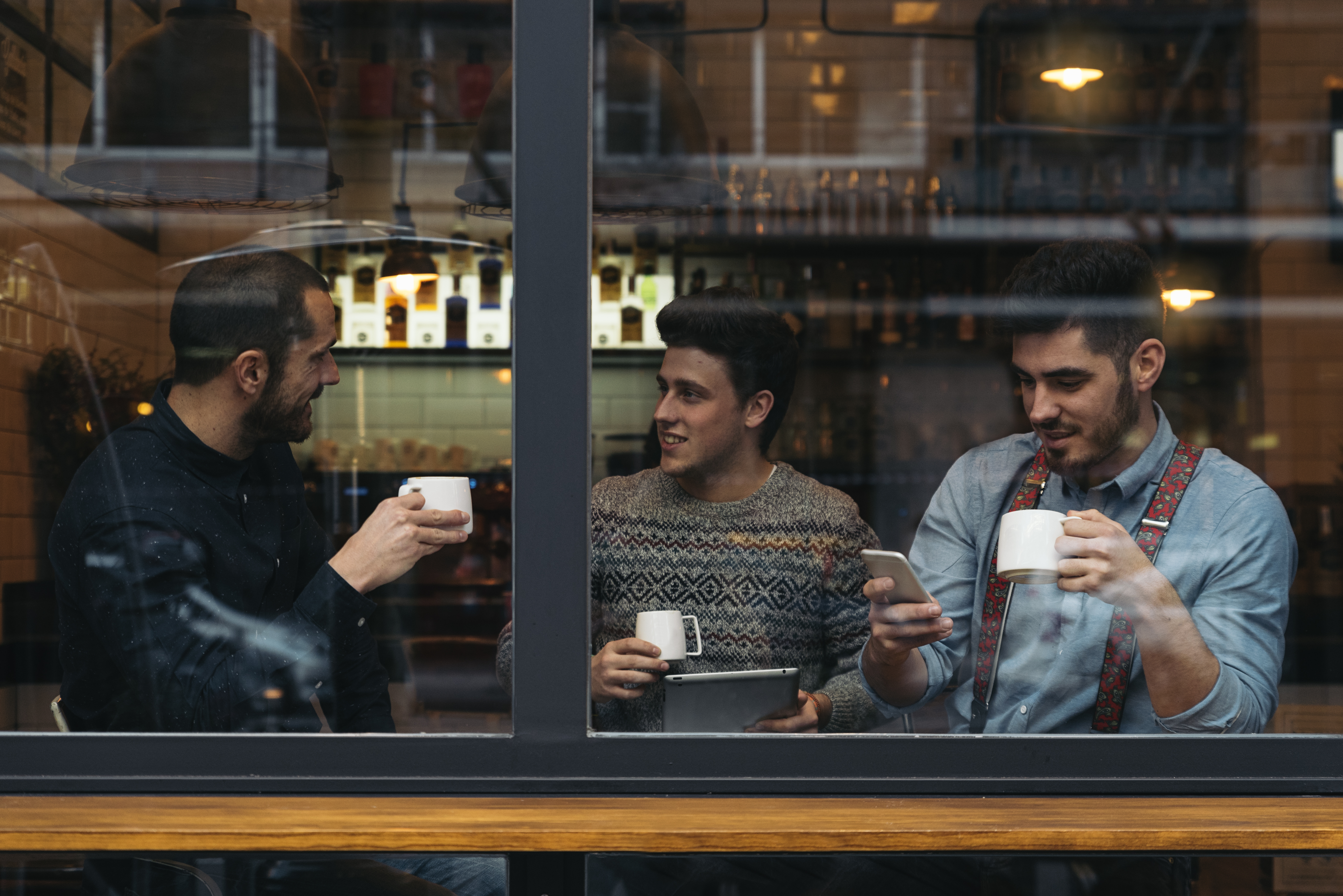 three men sitting in coffee shop window, what he wants you to say