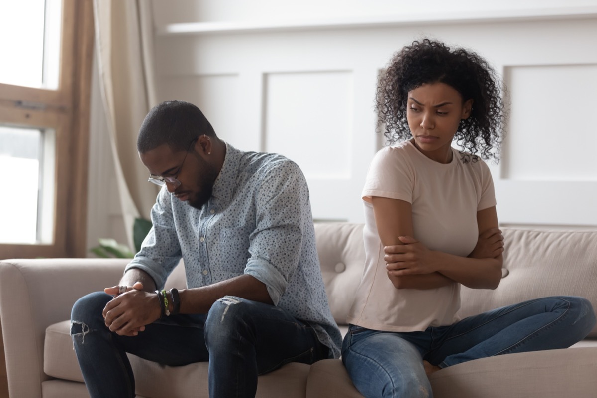 A couple sitting on a couch angry at one another. 