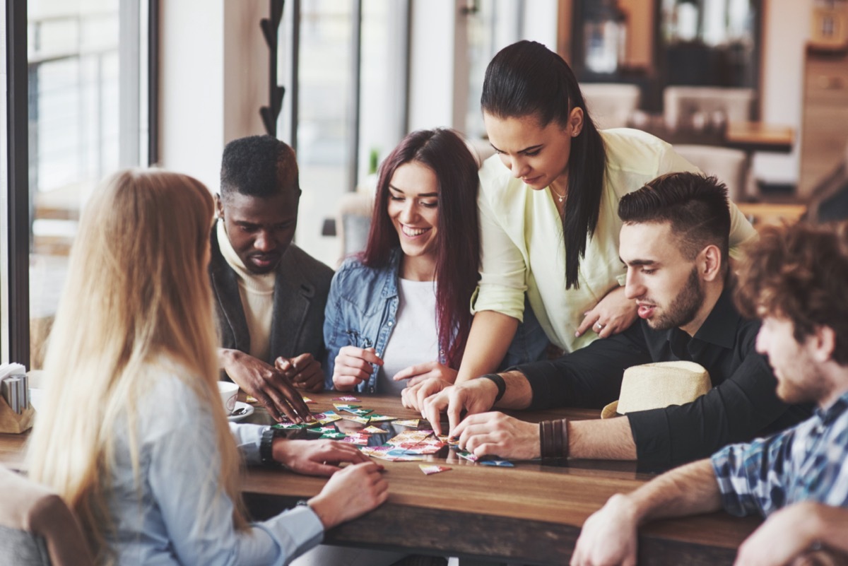 a group of friends looking at items and cards on a table for game