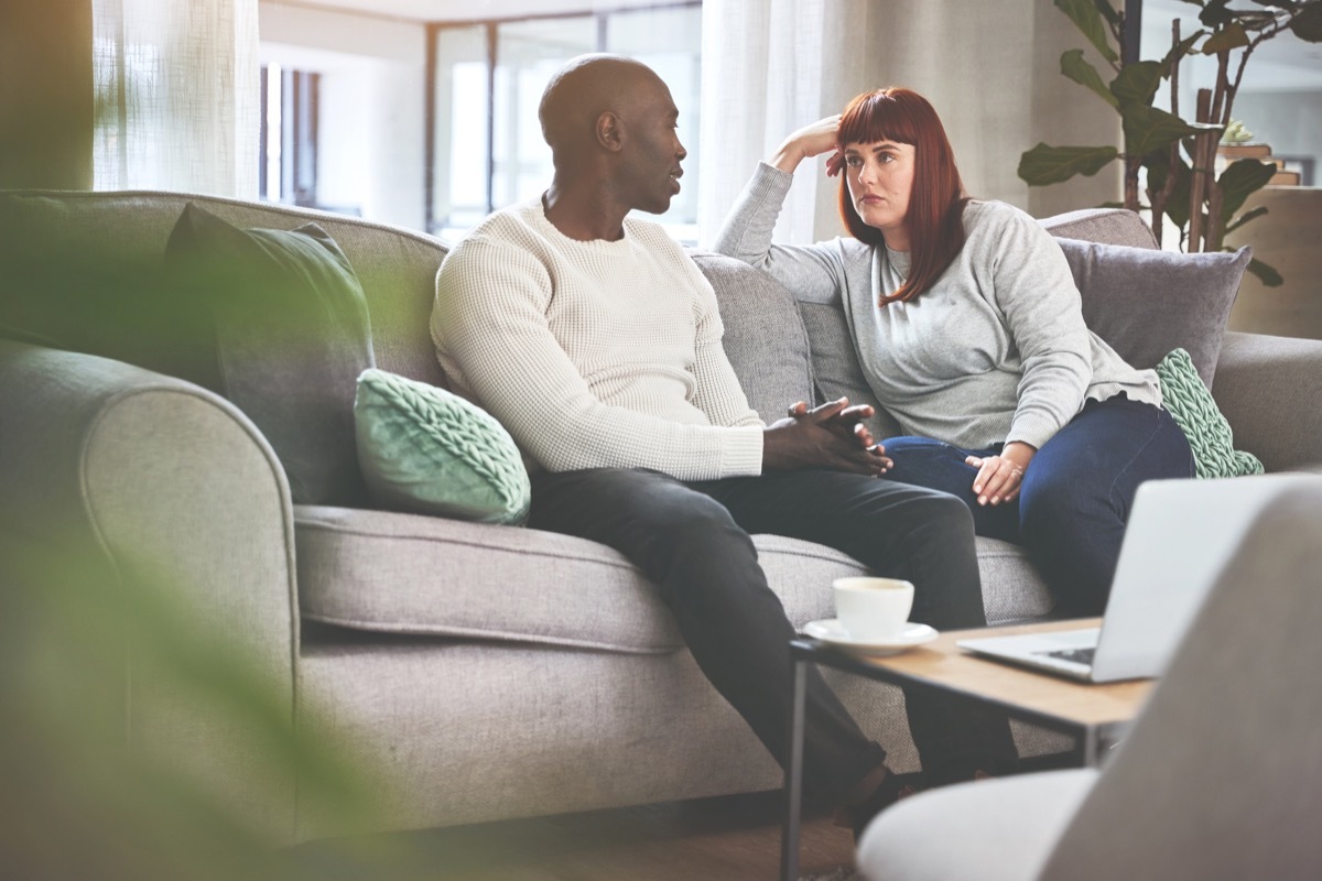 A couple talking on the sofa at home. A young man and woman having a serious discussion on the couch