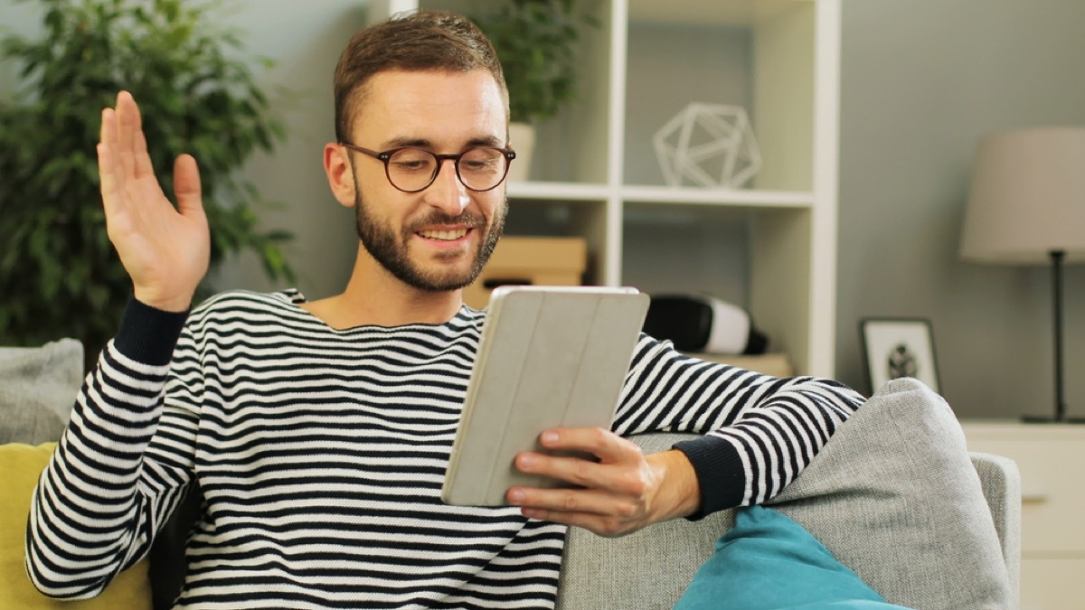 young white man waving at someone on his tablet