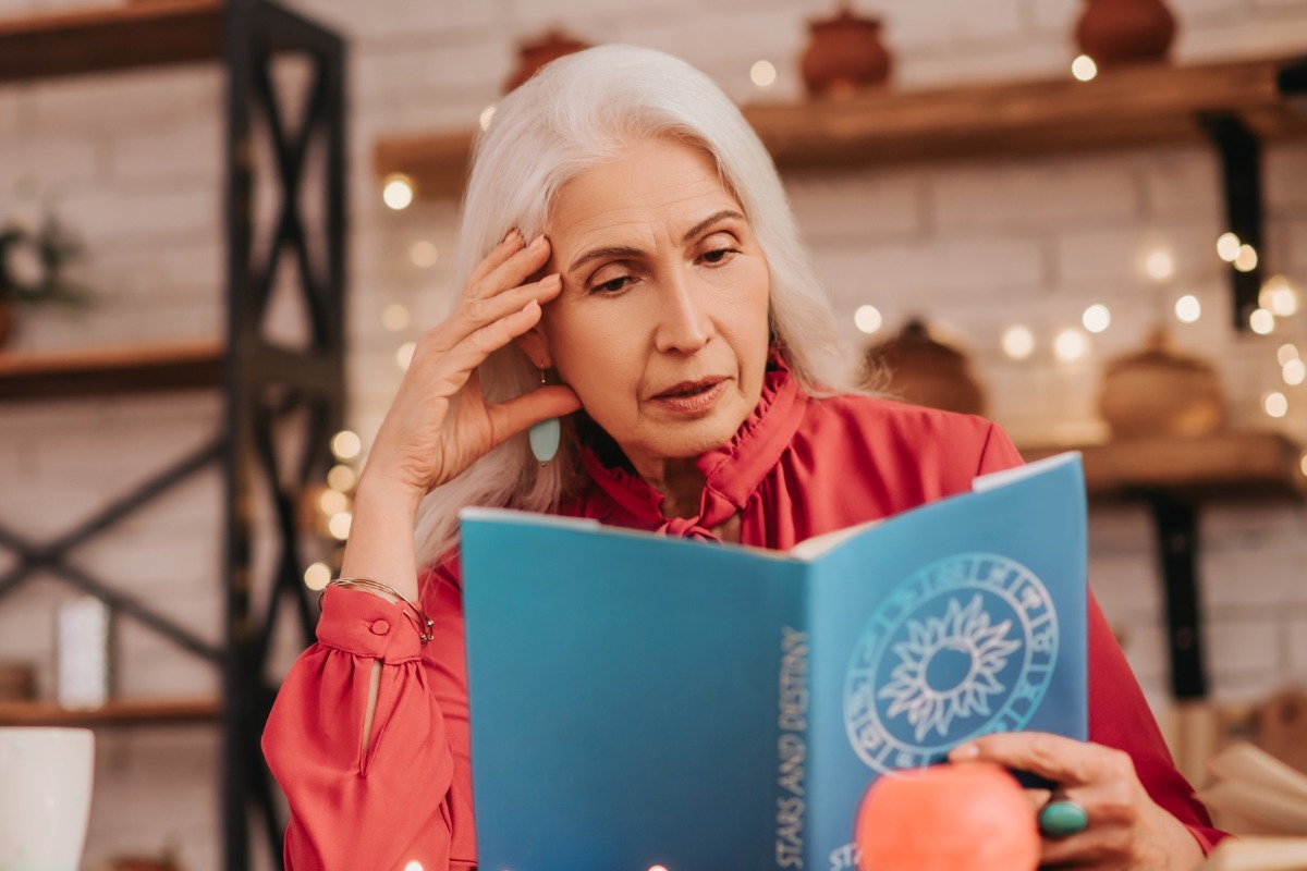 older woman reading astrology book