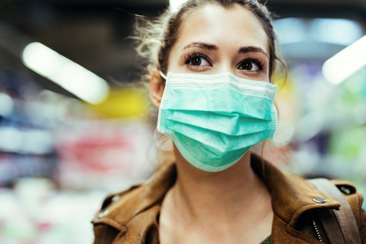 Woman wearing protective mask on her face while being in the store during coronavirus epidemic