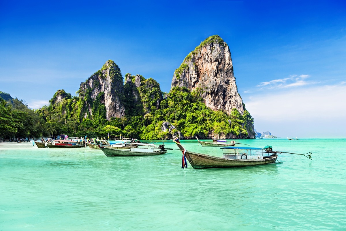 three boats in turquoise water with tropical islands