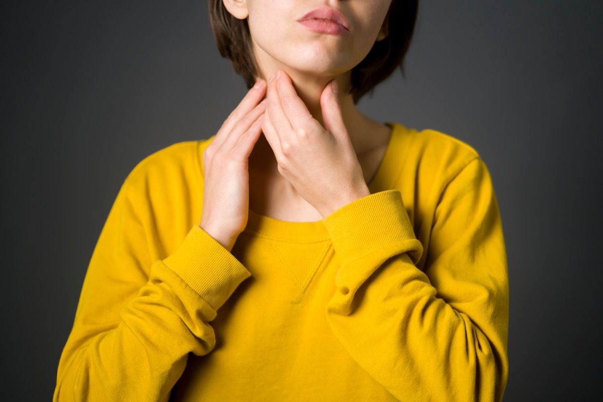 Woman checks the thyroid gland with her hands, keeps her palms on the neck.