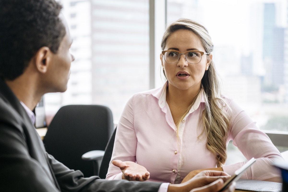 Two business people sitting in office having conversation, woman looking towards man with concerned expression