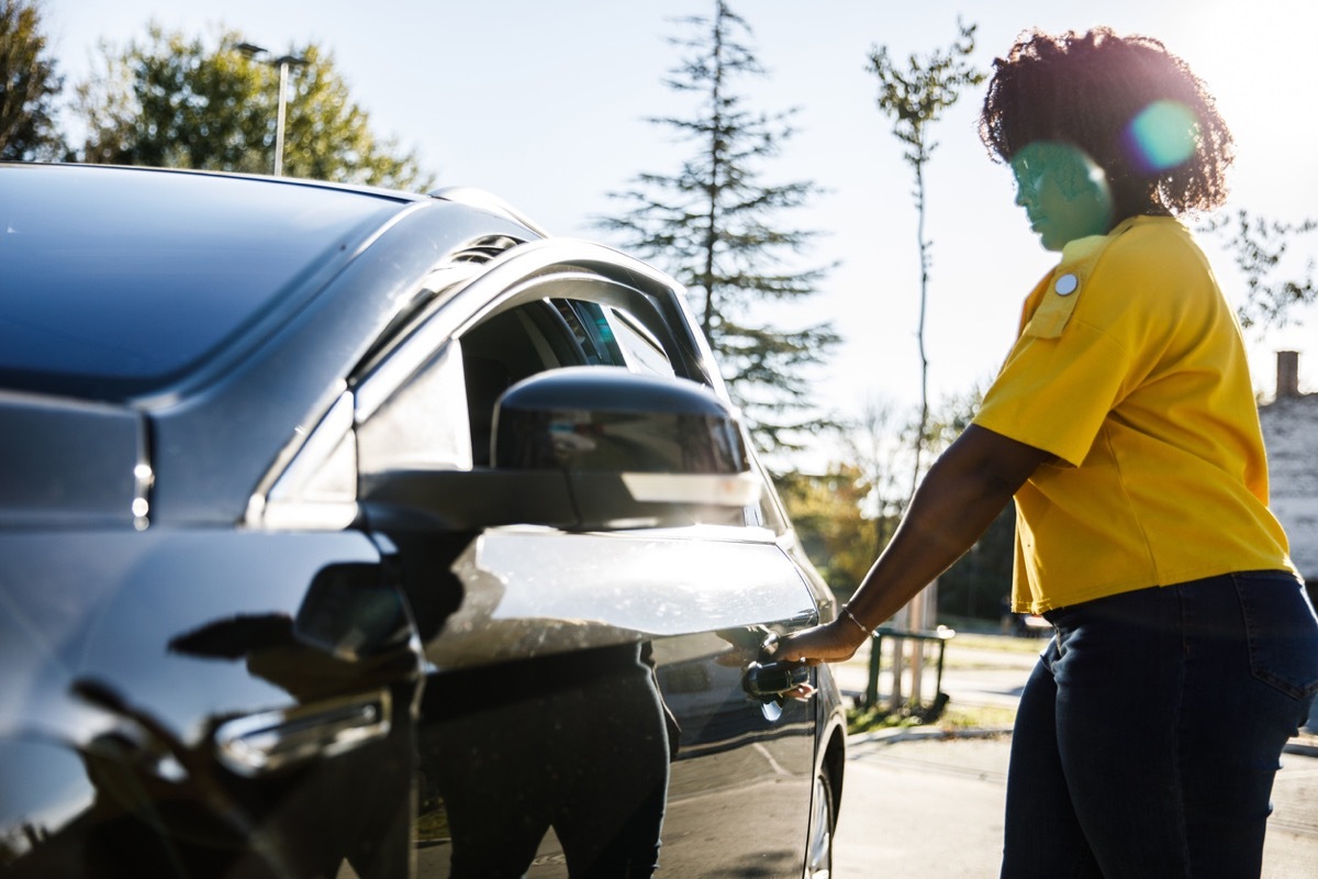 woman opening a door on the driver's side before entering her car.