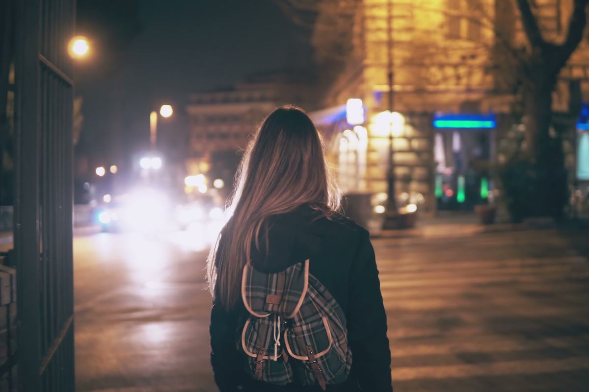 Back view of young woman walking late at night in the city centre