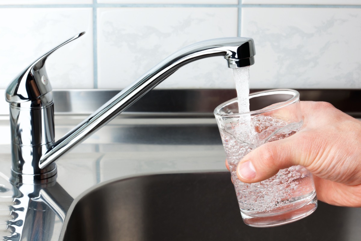 hand filling glass cup with tap water