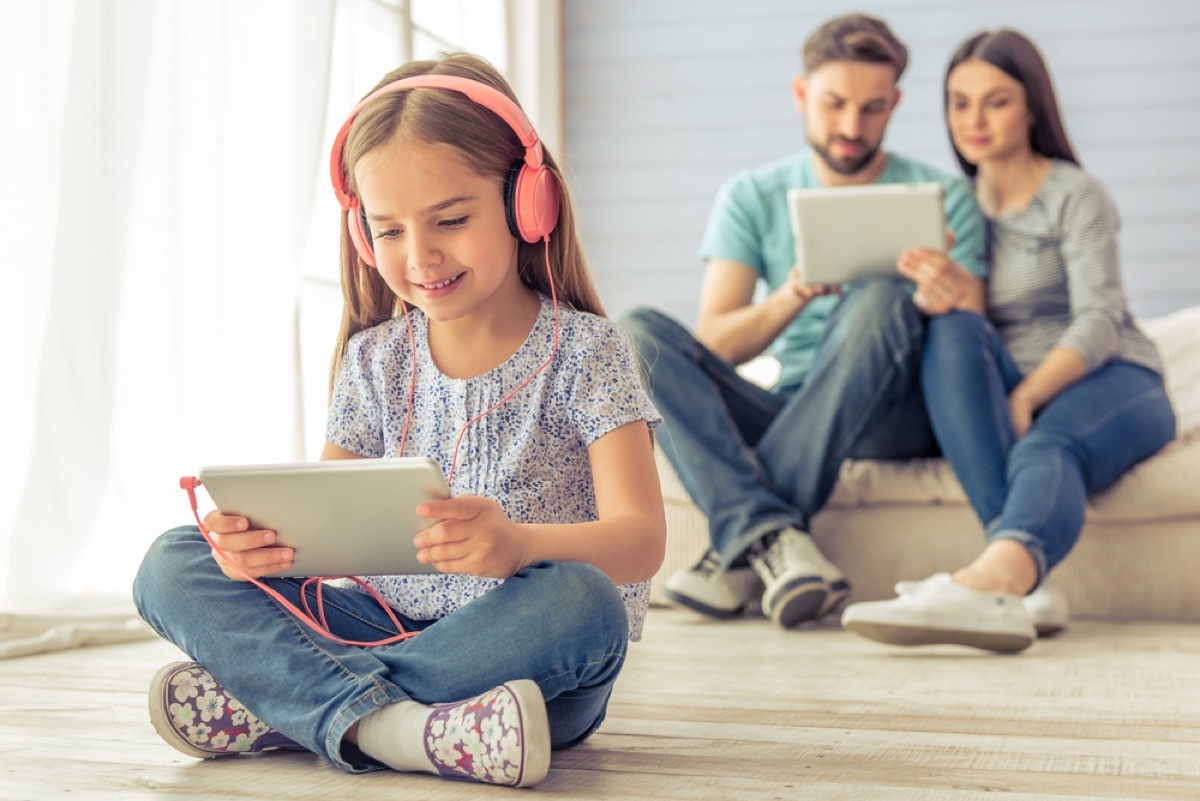 young girl with headphones on tablet, ways parenting has changed