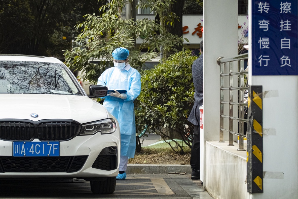 Security nurse take temperature of the person entering the hospital with surgical mask.