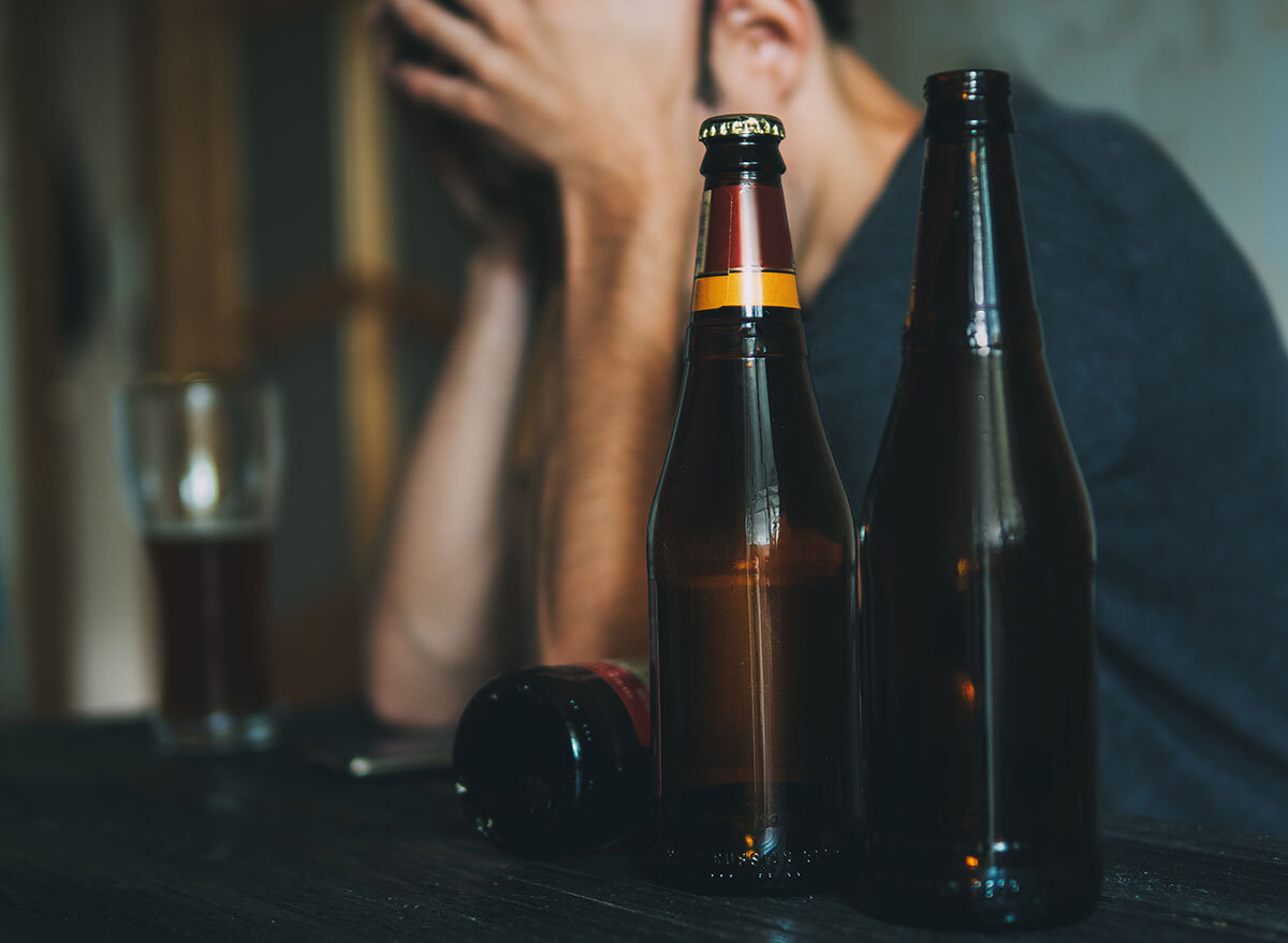 man holding head at bar with beers - how does alcohol affect the brain