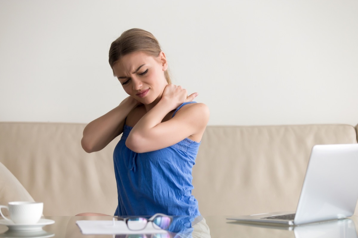 Tired woman feeling neck pain, massaging tense muscles, suffering from chronic shoulder back ache after long work on laptop computer at home, sedentary work, incorrect posture problems, fibromyalgia