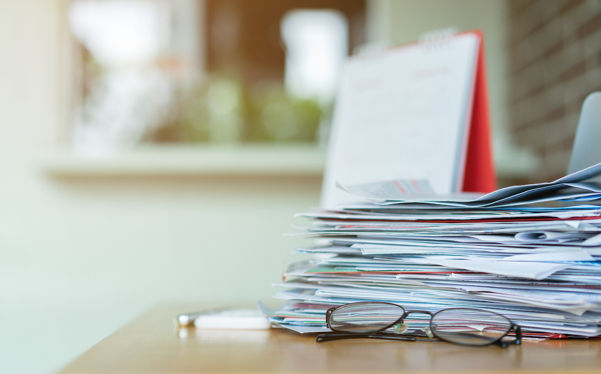 Pile of mail on a table with a pair of glasses