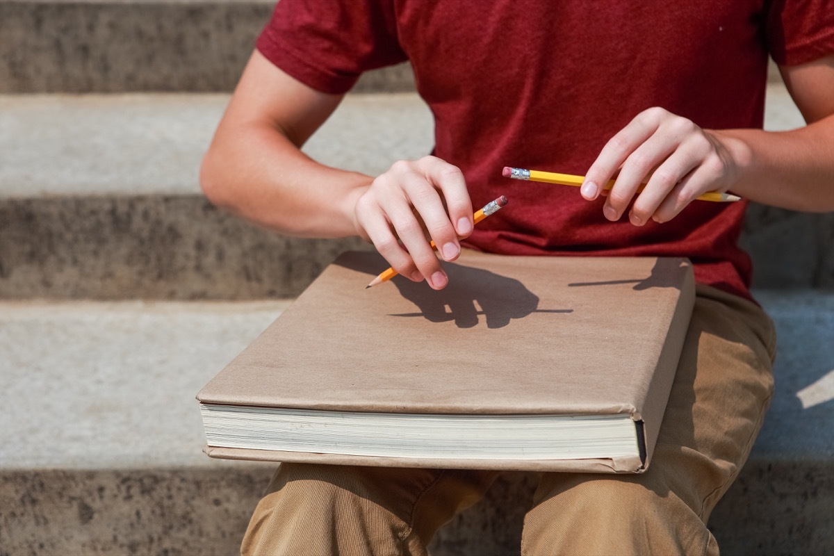 Boy feeling antsy and tapping his pencils on his notebook