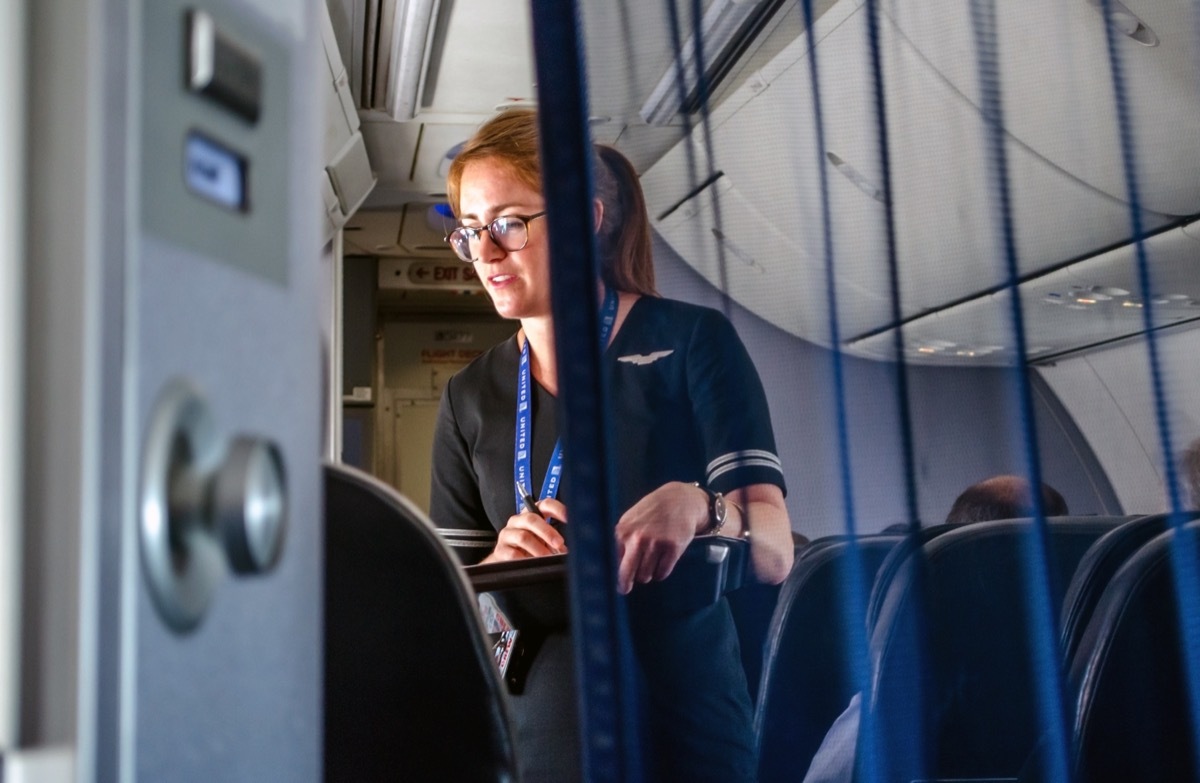 United airlines flight USA; a flight attendant is seen helping travelers in first class on an airplane in mid flight