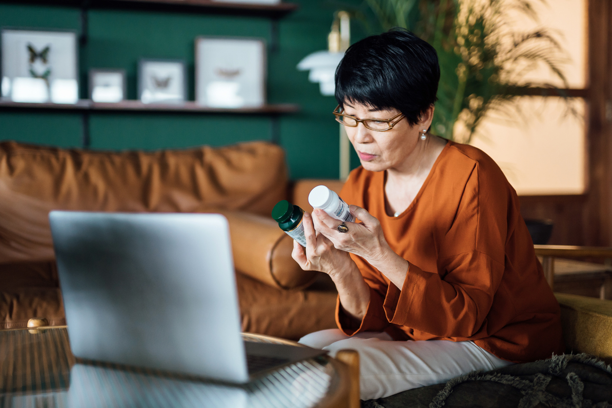 Woman in front of computer looking at two medicine containers.