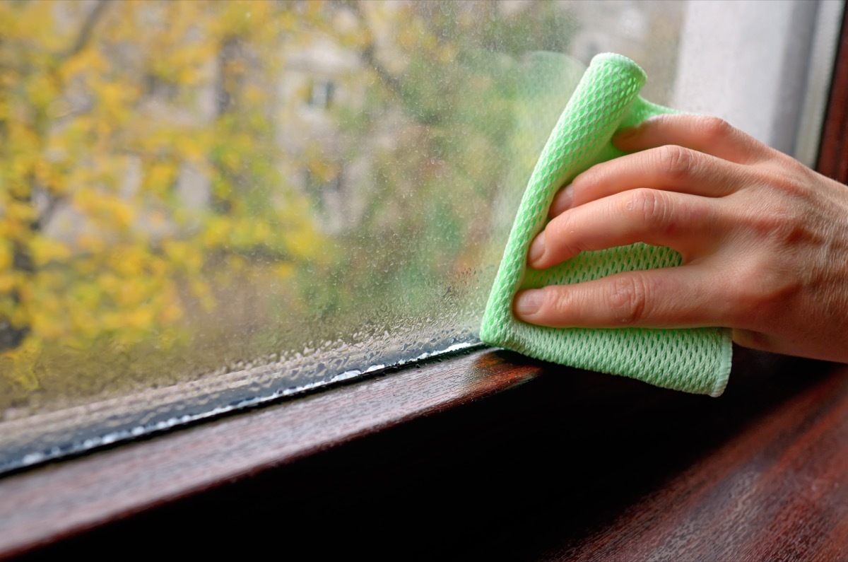 hand cleaning a damp basement window with a cloth